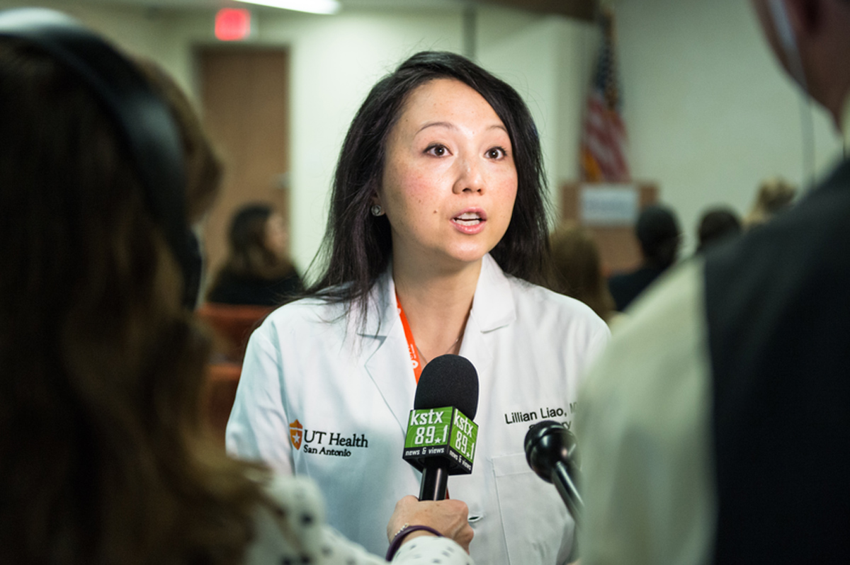 Lillian Liao is dressed in a white coat and talks to news reporters