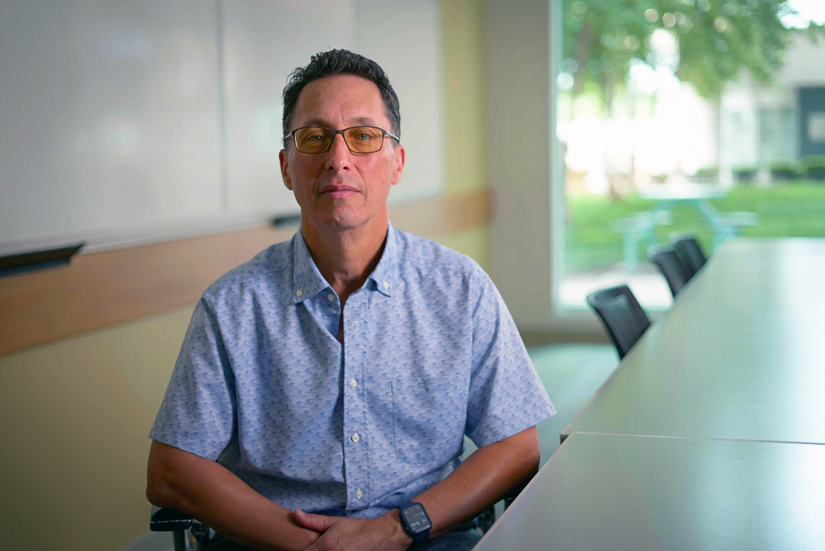 Richard Kamin is seated at a conference table, wearing a light blue sport shirt